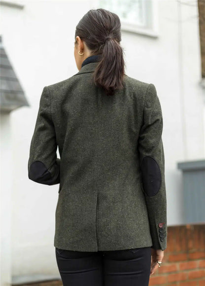 Person wearing a green blazer with black elbow patches outdoors.