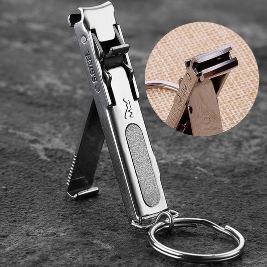 A stainless steel nail clipper keychain shown open on a dark textured surface, with a circular inset close-up of the clipper mechanism and a metal key ring attached.