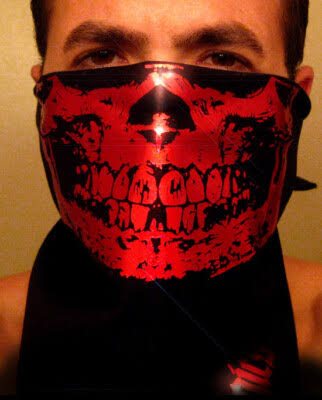 Person wearing a red and black skull face mask, bike riding mask Pakistan, against a neutral background.